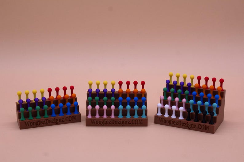 May include: Three wooden display stands with rows of colorful plastic pegs. The stands are labeled "WoogiezDesignz.COM".