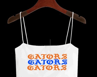May include: White spaghetti strap crop top with the word "GATORS" repeated three times in orange and blue lettering.