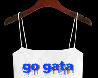 May include: White spaghetti strap crop top with the text "go gata" in blue and orange dripping paint letters.