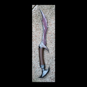 May include: A black and red curved dagger with a brown leather wrapped handle. The dagger has a serrated edge and a pointed tip.