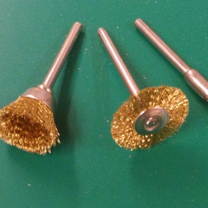 May include: Three gold-coloured wire brushes with metal handles. The brushes are different sizes and shapes.
