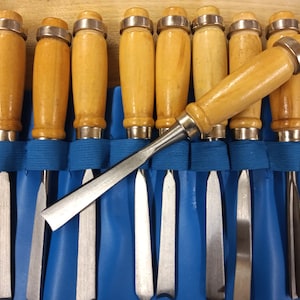 May include: A set of wood carving chisels with wooden handles and metal blades, arranged in a blue carrying case.