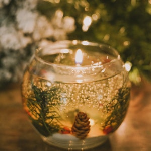 shalant holiday gel candles Pine and snow candles made with pine garland pine cones and sugar snow in clear gel wax. jelly candle in a glass bowl. These candles have a refillable glass votive in the center. Gel wax is scented with a pine balsam scent