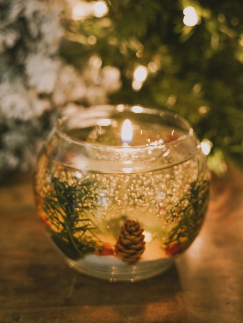 shalant holiday gel candles Pine and snow candles made with pine garland pine cones and sugar snow in clear gel wax. jelly candle in a glass bowl. These candles have a refillable glass votive in the center. Gel wax is scented with a pine balsam scent