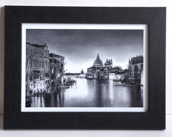 May include: A black and white pencil drawing of a cityscape with a large church in the distance. The drawing is framed in a black frame.