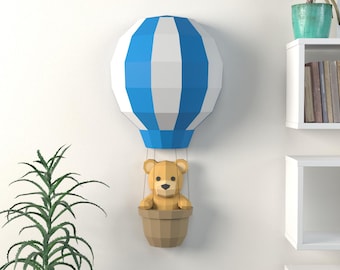 May include: A wall-mounted hot air balloon decoration with a blue and white striped balloon, a brown basket, and a teddy bear. The decor is a whimsical addition to a nursery or child's room.
