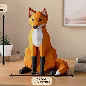 Pode incluir: Uma escultura geom&eacute;trica de raposa laranja, com 40 cm de altura e largura, com pernas pretas e peito e ponta da cauda brancos. A raposa &eacute; feita de papel ou cart&atilde;o dobrado e est&aacute; sobre uma superf&iacute;cie de madeira.