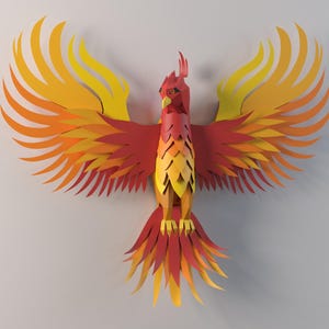 Op de afbeelding: Een papieren phoenix sculptuur met uitgespreide vleugels. De vogel heeft lagen rood, oranje en geel papier, waardoor een levendig, driedimensionaal effect ontstaat. Het kunstwerk is gemonteerd op een effen, lichtgekleurde achtergrond.