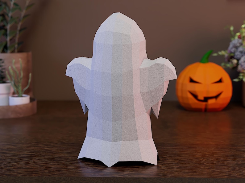 May include: A low-poly ghost figurine crafted with a matte white finish, featuring a geometric, faceted surface design. The ghost has a rounded head, two outstretched arms, and a pointed base, creating a structured, angular appearance.