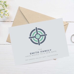 Könnte beinhalten: Eine hellgraue Ankündigungskarte mit einem geometrischen Ziel-Design in Türkis und Marineblau. Die Karte enthält den Text "THE SMITH FAMILY HAVE MOVED TO A NEW BASE" und eine Adresse. Ein brauner Umschlag befindet sich hinter der Karte.