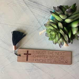 May include: Wooden bookmark with a black tassel, a cross, and the text "I trust the next chapter because I know its author".