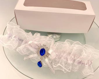Strumpfband aus weißer Spitze mit blauer Kristallbrosche