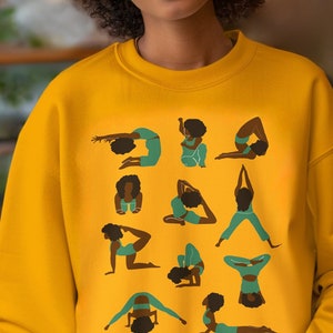 May include: A yellow sweatshirt with a graphic print of multiple women in various yoga poses. The women are all black with green and blue clothing.