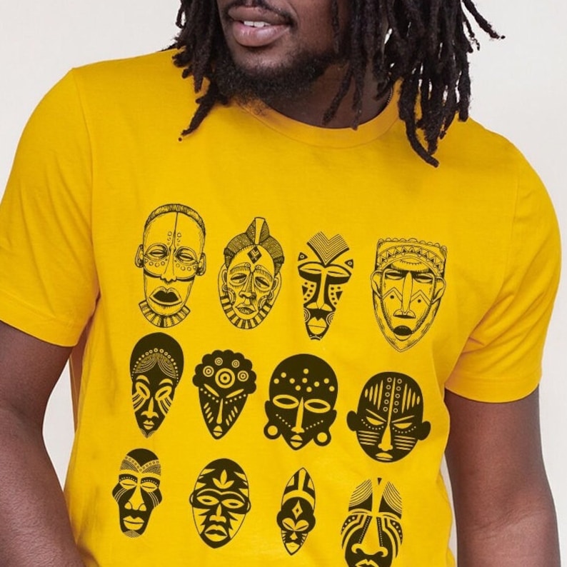 May include: A yellow t-shirt with a black and white design of African masks. The masks are arranged in a grid pattern and feature various shapes and designs.