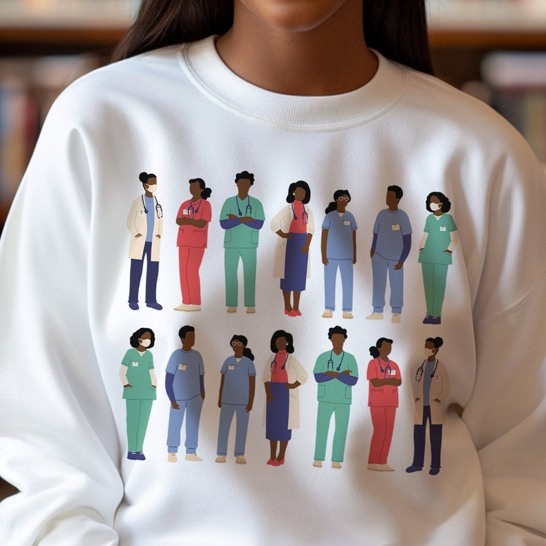 May include: White sweatshirt with a graphic print of a group of people wearing medical scrubs and masks. The people are all different races and genders. The text on the sweatshirt says "Healthcare Heroes".