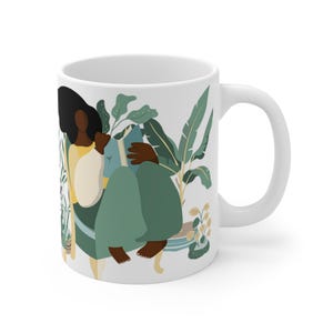 May include: White ceramic mug with a colorful illustration of a person sitting in a chair reading a book surrounded by plants. The person has dark skin and is wearing a yellow shirt and green pants.