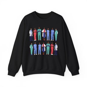May include: Black sweatshirt with a graphic print of a group of diverse healthcare workers wearing scrubs and masks. The workers are standing in a line, with their arms crossed.