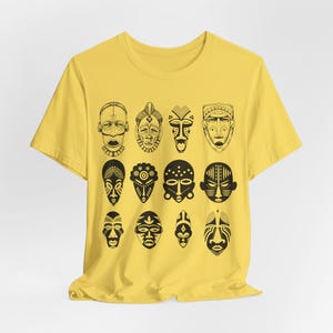 May include: A yellow t-shirt with a black and white print of 12 African tribal masks.