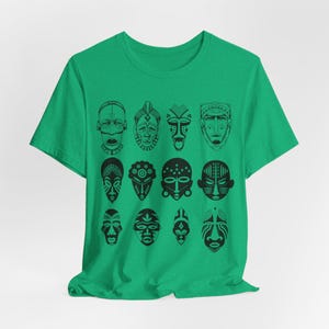 May include: A green t-shirt with a black and white design of 12 African tribal masks. The masks are arranged in a grid pattern.