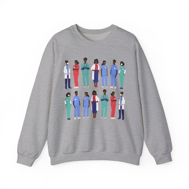 May include: A gray sweatshirt with a graphic print of a group of diverse healthcare workers wearing scrubs and masks. The workers are standing in a line, and the graphic is centered on the sweatshirt.