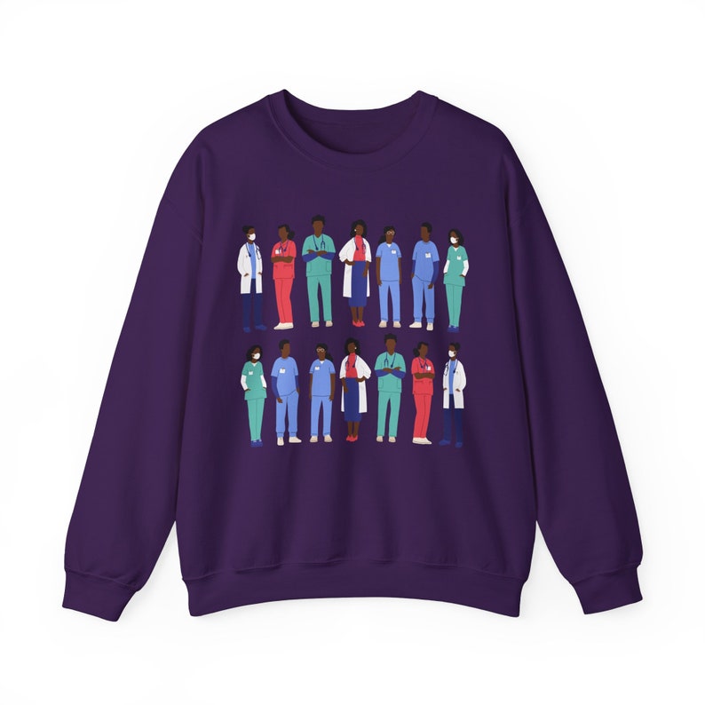 May include: Purple sweatshirt with a graphic of a group of diverse healthcare workers wearing face masks and scrubs. The workers are standing in two rows, with the top row slightly overlapping the bottom row. The graphic is centered on the sweatshirt.