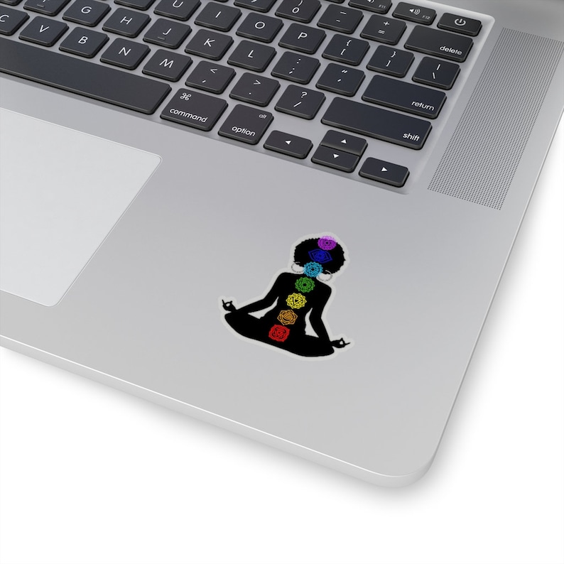 May include: A black silhouette of a person meditating with seven colorful chakras, representing the seven energy centers of the body, on a white background.