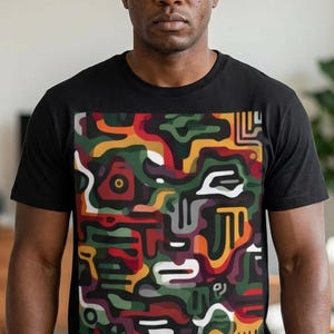 May include: Black crew neck t-shirt featuring a colorful abstract design. The graphic includes shapes in red, green, yellow, and white, creating a unique pattern. The shirt is made of a soft material.