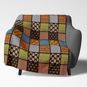 May include: A colorful throw blanket with a patchwork design featuring geometric patterns, hearts, and stylized faces. The blanket is made up of squares in shades of red, yellow, green, blue, black, and white.