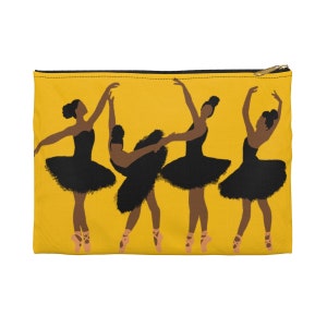 Pode incluir: Uma bolsa amarela com z&iacute;per com um gr&aacute;fico de quatro bailarinas em tutus pretos e sapatilhas de ponta. As bailarinas est&atilde;o em v&aacute;rias poses de dan&ccedil;a em um fundo amarelo. A bolsa tem um z&iacute;per dourado.