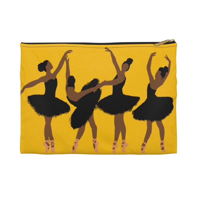Pode incluir: Uma bolsa amarela com z&iacute;per com um gr&aacute;fico de quatro bailarinas em tutus pretos e sapatilhas de ponta. As bailarinas est&atilde;o em v&aacute;rias poses de dan&ccedil;a em um fundo amarelo. A bolsa tem um z&iacute;per dourado.
