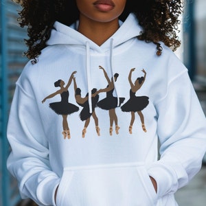 May include: White hoodie featuring a graphic of four ballet dancers in black tutus and pointe shoes. The dancers are in various poses, with arms raised and legs extended. The design is centered on the front of the hoodie.
