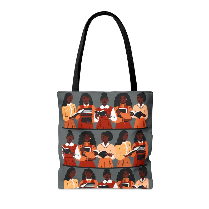 Puede incluir: Un bolso tote con asa negra y cuerpo gris. El cuerpo del bolso presenta un patr&oacute;n repetido de ilustraciones de mujeres leyendo libros. Las mujeres visten varios atuendos en tonos naranja, rojo y amarillo.