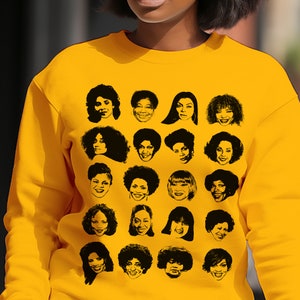 May include: Mustard yellow sweatshirt featuring a grid of black and white portraits of women. The portraits are stylized line drawings with varying hairstyles and expressions. The sweatshirt is a solid color with a crew neck.