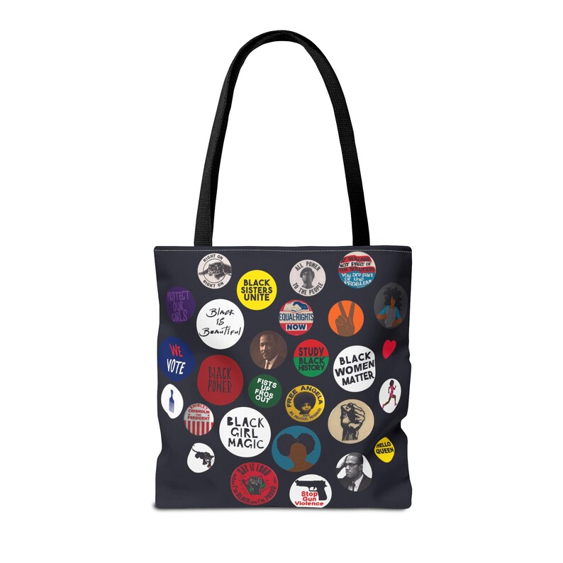May include: Black tote bag featuring a collage of colorful circular graphics with text and illustrations. The graphics include phrases like "Black Sisters Unite," "Black Girl Magic," and "Black Women Matter." The bag has black handles.