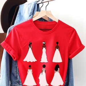 May include: A red t-shirt featuring six illustrations of women in white wedding dresses. The dresses have various necklines and silhouettes. The illustrations are set against a solid red background, creating a striking contrast.