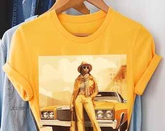 May include: A yellow t-shirt with a graphic print of a woman wearing a hat and sunglasses standing next to a yellow car.