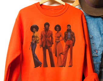 May include: Orange sweatshirt with a graphic print of four people with afro hairstyles wearing 1970s clothing.
