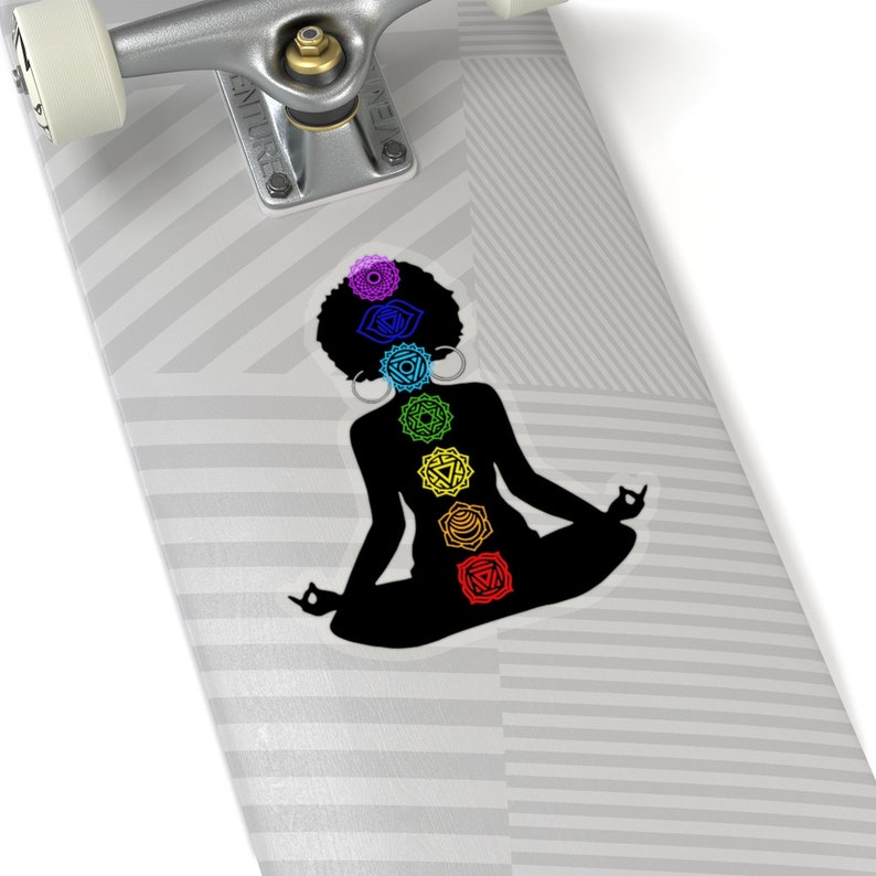 May include: A black silhouette of a person sitting in a yoga pose with the seven chakras represented in colorful symbols along the spine.