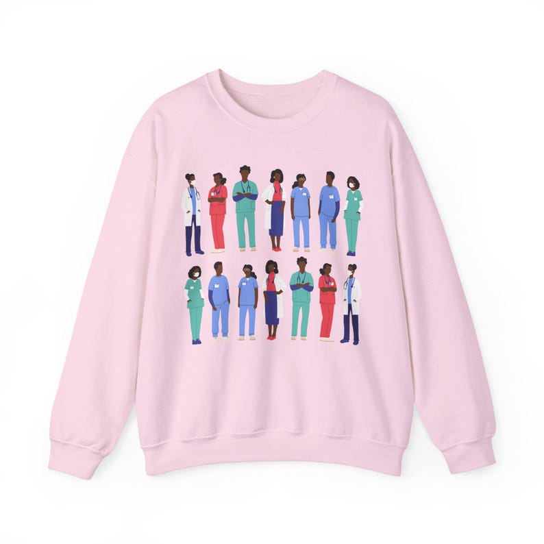 May include: Pink sweatshirt with a graphic print of a diverse group of healthcare workers wearing scrubs and masks. The graphic features a variety of skin tones and hairstyles.
