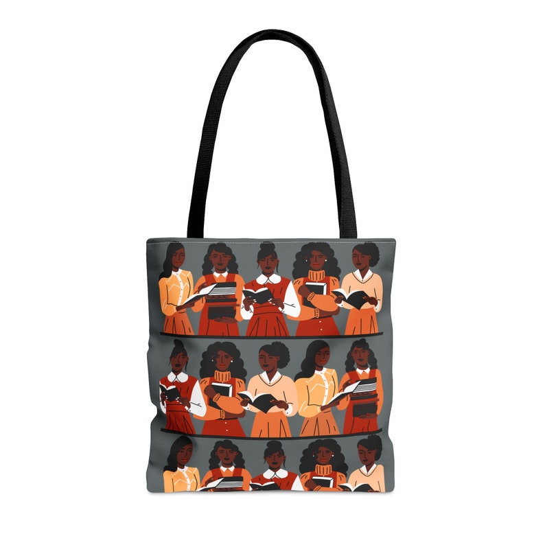 Puede incluir: Bolso tote gris con asas negras. Presenta una ilustraci&oacute;n repetida de mujeres leyendo libros. Las mujeres visten varios atuendos con tonos naranja, rojo y amarillo. Ideal para llevar libros y otros art&iacute;culos.