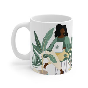 May include: White ceramic mug with a colorful illustration of a person sitting in a chair surrounded by plants. The person is wearing a green shirt and has long black hair. The mug has a handle on the left side.