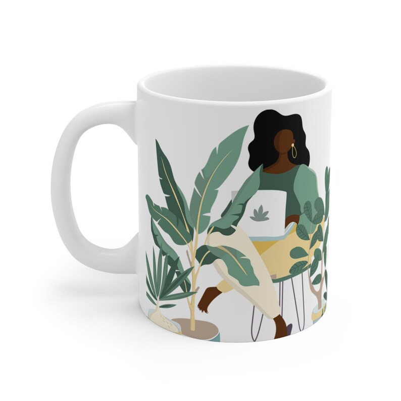 May include: White ceramic mug with a colorful illustration of a person sitting in a chair surrounded by plants. The person is wearing a green shirt and has long black hair. The mug has a handle on the left side.