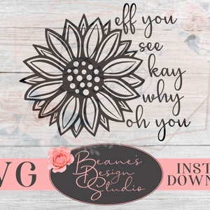 以下が含まれることがあります： 白黒のひまわりグラフィックに「eff you see kay why oh you」というテキストが書かれています。グラフィックは白い木製の背景に、ピンクのバナーに「SVG」と黒の楕円形に「Beane's Design Studio」というテキストが書かれています。