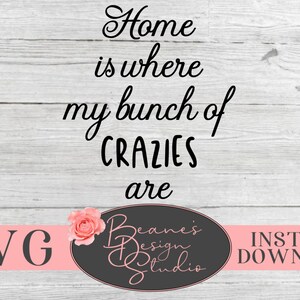 May include: A white woodgrain background with black text that reads "Home is where my bunch of CRAZIES are". Below the text is a pink rose and a black oval with the text "Beane's Design Studio" in white. Below the oval is a pink banner with the text "SVG INSTANT DOWNLOAD" in white.
