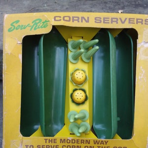 May include: A yellow and green box with the text "Serv-Rite CORN SERVERS" and "THE MODERN WAY TO SERVE CORN ON THE COB". The box contains three green corn holders with yellow corn tops.