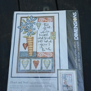 May include: A Dimensions counted cross stitch kit titled "Heart and Soul" with a floral and heart design. The kit includes cotton thread, a 14-count ivory Aida, thread palette, needle, and instructions. The design features the text "Put your whole heart and soul into what you love."