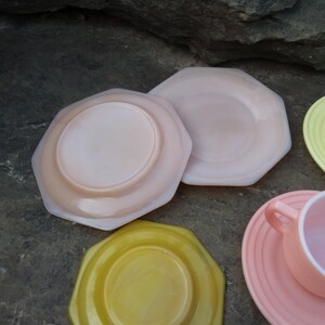 May include: Set of four pastel-colored vintage glass plates. The plates are octagonal and have a raised rim. The colors are pink, yellow, and a lighter shade of pink.