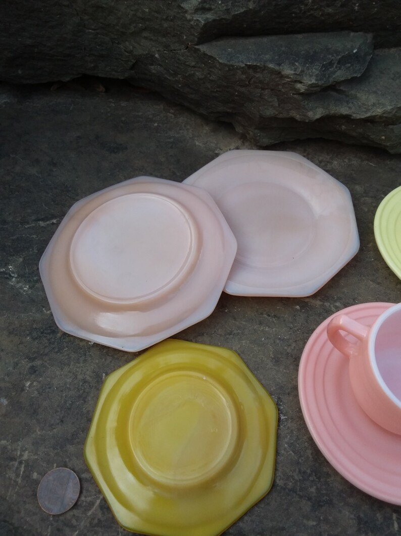 May include: Set of four pastel-colored vintage glass plates. The plates are octagonal and have a raised rim. The colors are pink, yellow, and a lighter shade of pink.