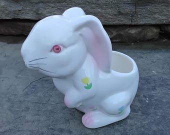 May include: White ceramic bunny planter with pink ears and painted flowers. The bunny has red eyes and a black nose.