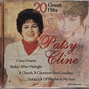 May include: A Patsy Cline 20 Great Hits CD case featuring a portrait of the artist in a white collared shirt with a red neck scarf. The cover includes the text Crazy Dreams, Walkin' After Midnight, A Church, A Courtroom And Goodbye, and Gotta Lot Of Rhythm In My Soul.